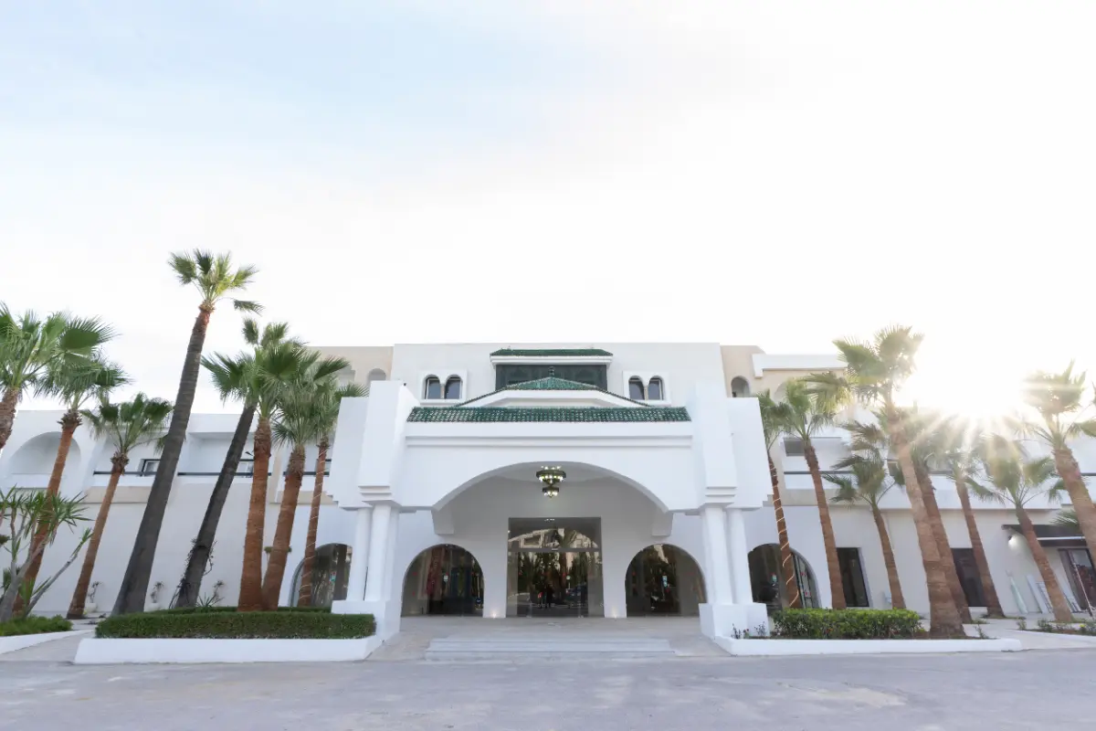 Entrée de l'Hôtel Hammamet Beach avec arcades blanches, zellige vert et palmiers à Hammamet, Tunisie