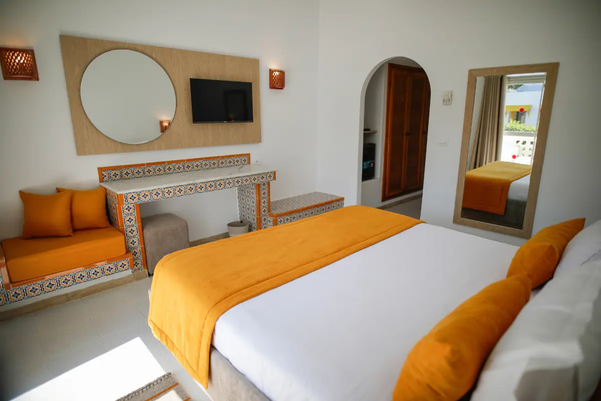 Intérieur spacieux du bungalow avec arche tunisienne, zellige et coin salon à l'Hôtel Hammamet Beach, Hammamet Tunisie