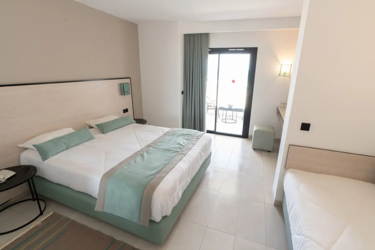 Vue d'ensemble de la chambre rénovée avec lit double, canapé et balcon à l'Hôtel Hammamet Beach, Hammamet Tunisie