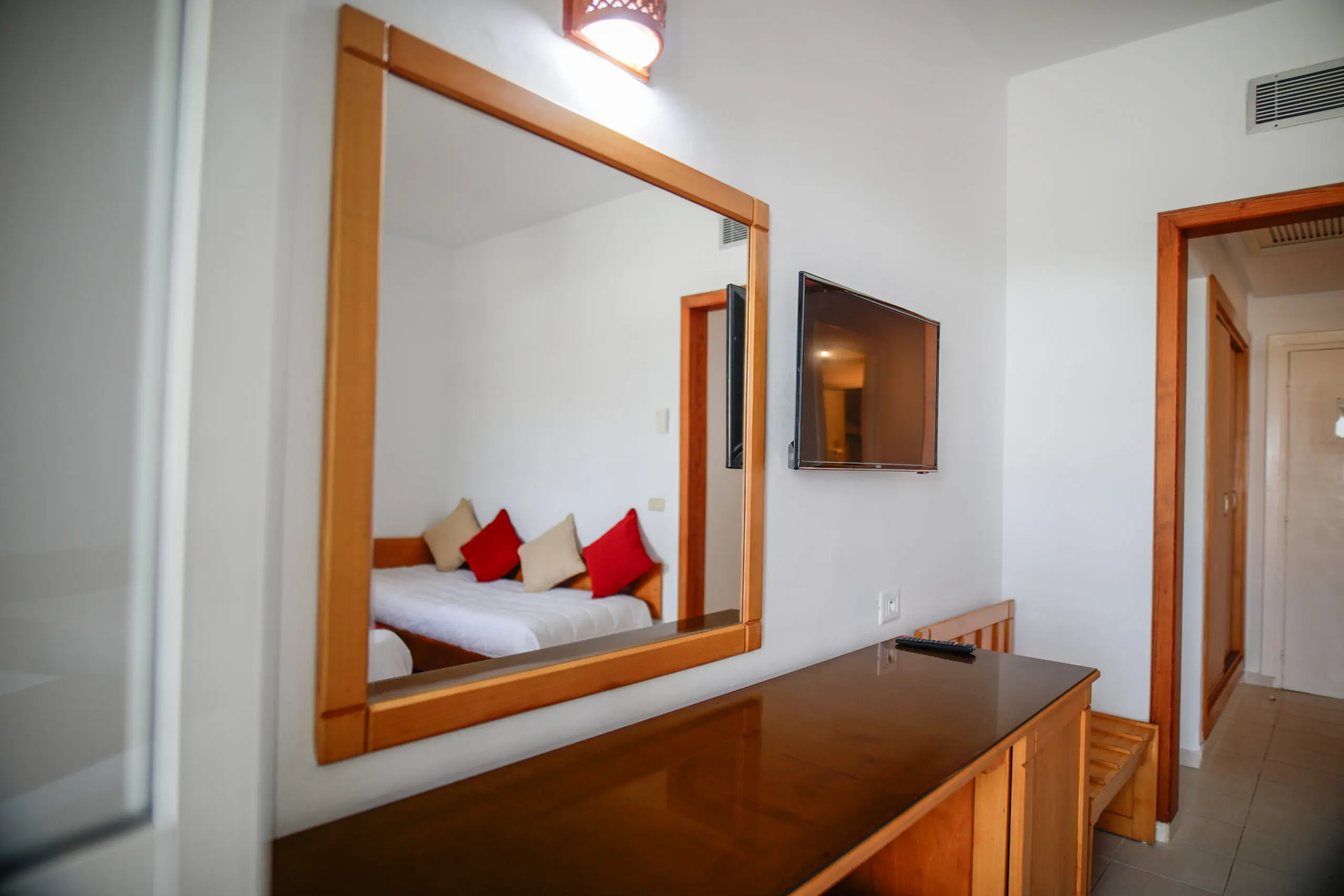 Chambre standard avec TV murale, coiffeuse en bois et miroir à l'Hôtel Hammamet Beach, Hammamet Tunisie
