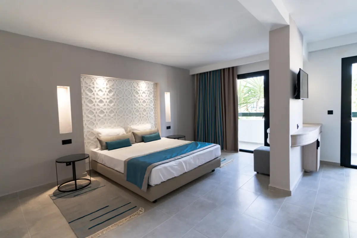 Vue d'ensemble de la chambre supérieure avec tête de lit moucharabieh, TV murale et balcon à l'Hôtel Hammamet Beach, Hammamet Tunisie