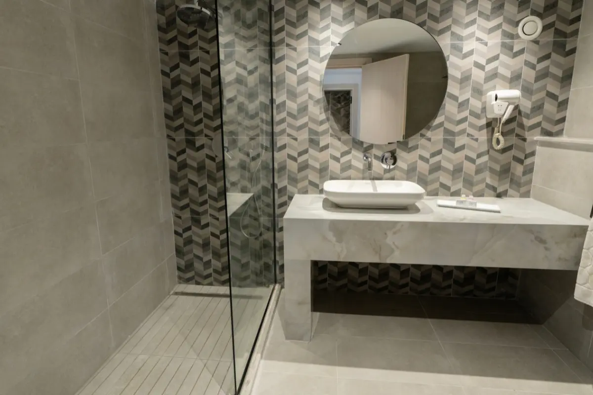 Salle de bain moderne avec douche italienne vitrée et vasque sur plan en marbre à l'Hôtel Hammamet Beach, Hammamet Tunisie